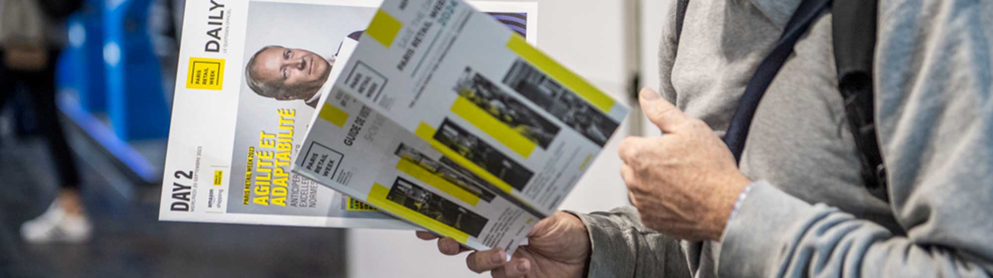 person reading a Paris retail Week magazine