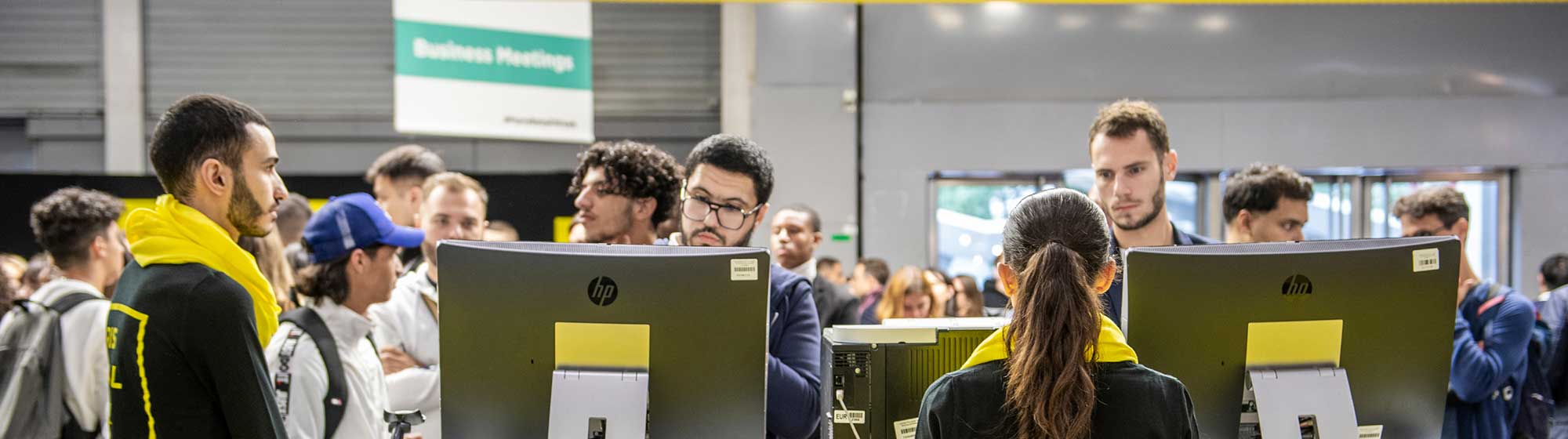 Visiteurs discutant avec les hôtes et hôtesses à l'accueil du salon