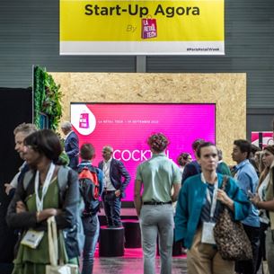 groupe de personne réunit au salon professionel Paris Retail Week et devant une bannière avec écrit start-up